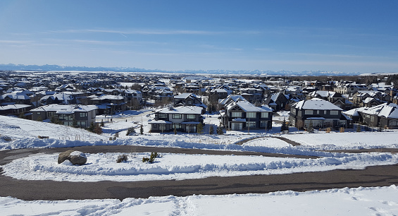 High angle overview of large residential development in winter.  New, Modern Large Homes. Rocky Mountains in background.