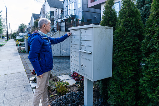 A man is unlocking a mailbox that is shared in the neighborhood.