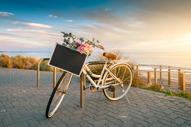 Vintage bicycle with text banner frame on a steering wheel parked near the beach at sunset time