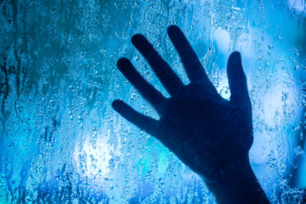 istock A hand is shown through a window with raindrops on the glass 2067350417