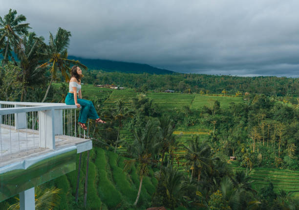 istock Woman sitting on the balcony and looking at Jatiluwih rice fields 2067363344