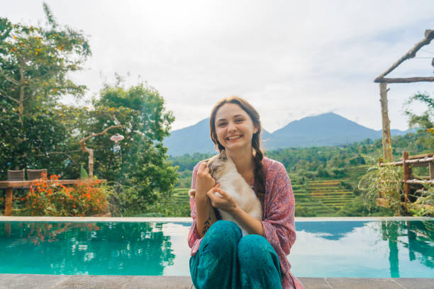 istock Woman sitting at the pool with her cat  on Bali 2067364524