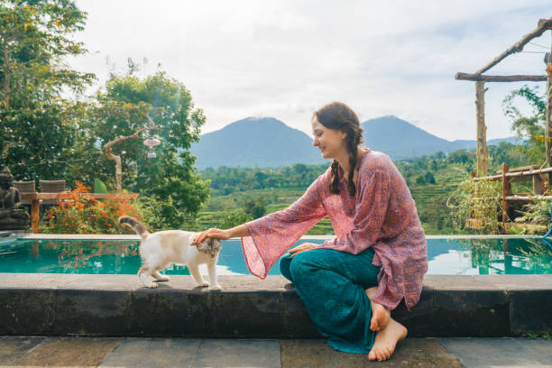 Woman sitting at the pool with her cat  on Bali