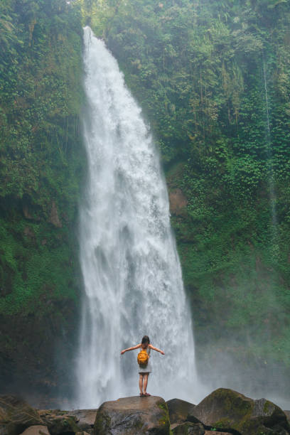 istock Woman standing near the refreshing waterfall on Bali 2067365573