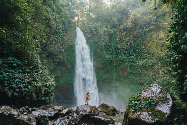 istock Woman standing near the refreshing waterfall on Bali 2067365575