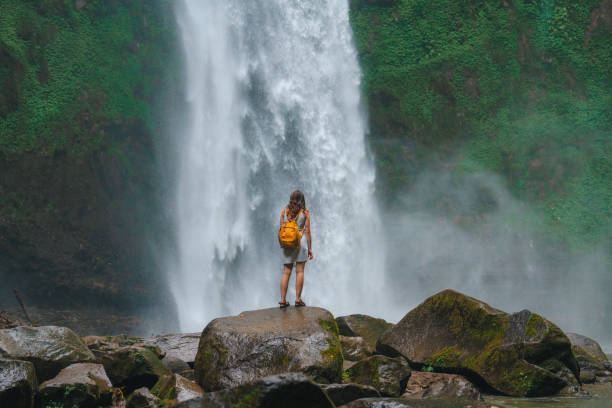 istock Woman standing near the refreshing waterfall on Bali 2067367121
