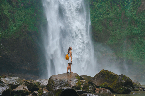 Carefree woman enjoying the serenity of powerful waterfall on Bali island