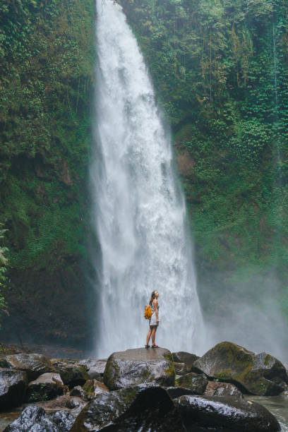 istock Woman standing near the refreshing waterfall on Bali 2067367123