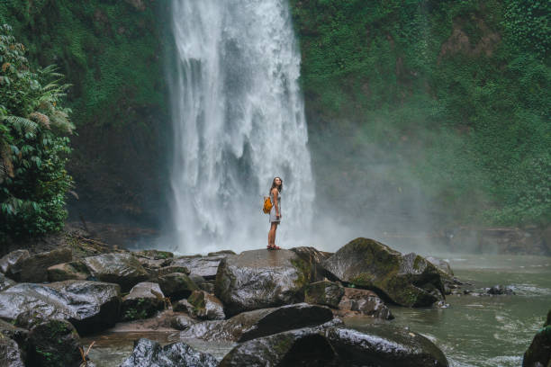 istock Woman standing near the refreshing waterfall on Bali 2067367124