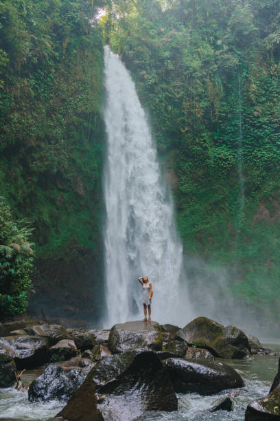 istock Woman standing near the refreshing waterfall on Bali 2067368691
