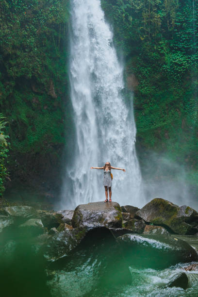 istock Woman standing near the refreshing waterfall on Bali 2067368692