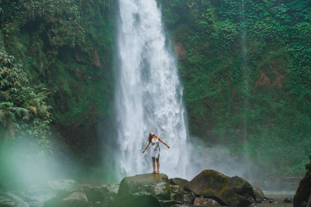 istock Woman standing near the refreshing waterfall on Bali 2067370270