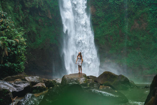 istock Woman standing near the refreshing waterfall on Bali 2067370271