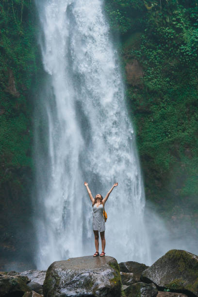 istock Woman standing near the refreshing waterfall on Bali 2067370273