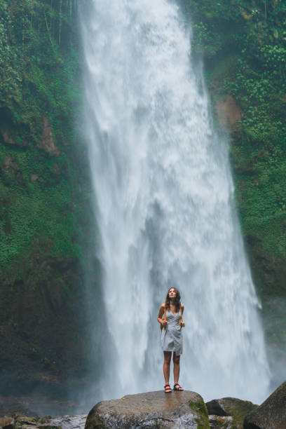 istock Woman standing near the refreshing waterfall on Bali 2067370274