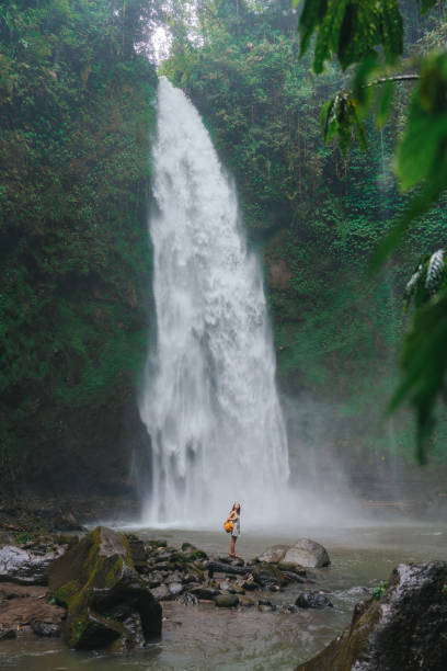 istock Woman standing near the refreshing waterfall on Bali 2067372392