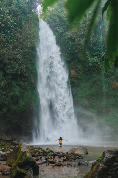 istock Woman standing near the refreshing waterfall on Bali 2067372393