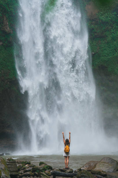 istock Woman standing near the refreshing waterfall on Bali 2067372394