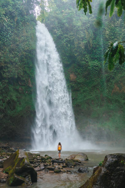 istock Woman standing near the refreshing waterfall on Bali 2067372396