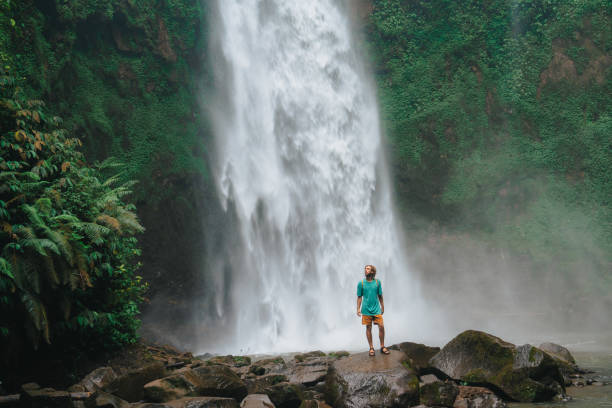 istock Man enjoying tropical waterfall  on Bali 2067373456