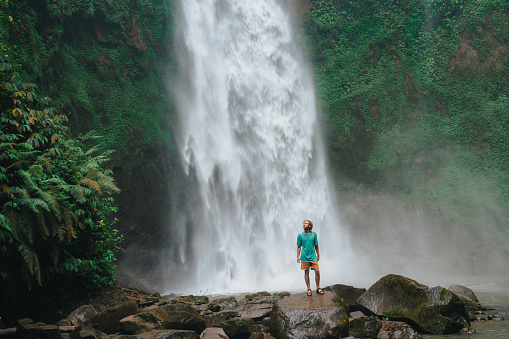 Cheerful man enjoying tropical waterfall  on Bali