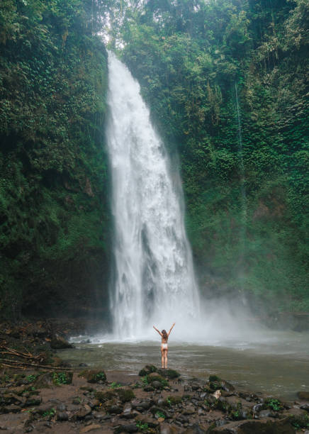 istock Woman standing near the refreshing waterfall on Bali 2067373989