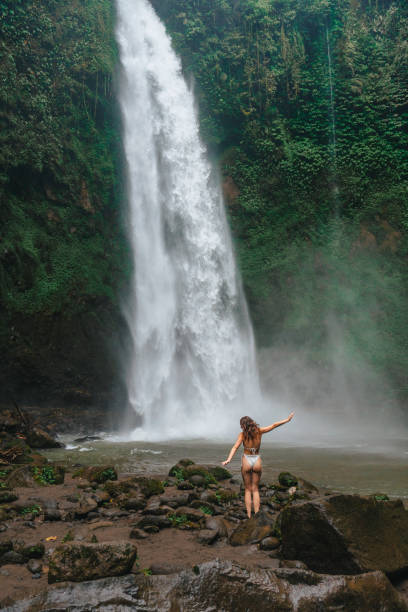 istock Woman standing near the refreshing waterfall on Bali 2067376593