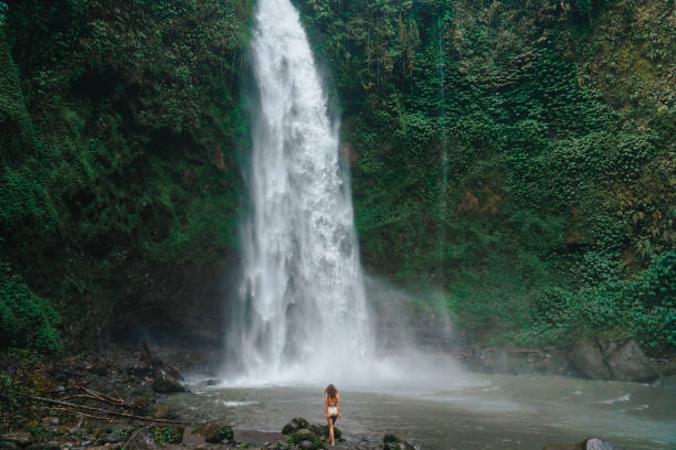 istock Woman standing near the refreshing waterfall on Bali 2067376594
