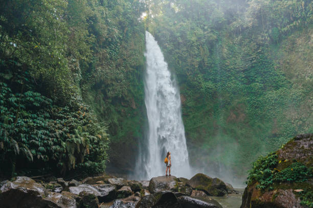 istock Woman standing near the refreshing waterfall on Bali 2067380189