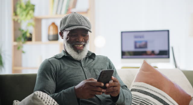 Phone, chat and senior man on sofa with funny meme, gif or social media  at home. Smartphone, streaming or old African person in a living room for retirement entertainment with online dating app