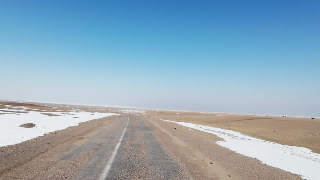Worn-out asphalt road in winter steppe