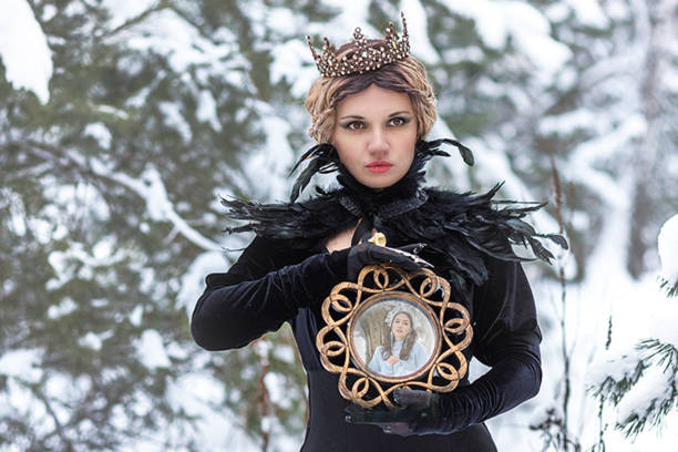 fashion concept. a beautiful young lady with blond hair and a long black dress, with a crown on her head, stands in a winter park. beautiful dark princess using a black magic spell. - women crown princess 20s стоковые фото и изображения