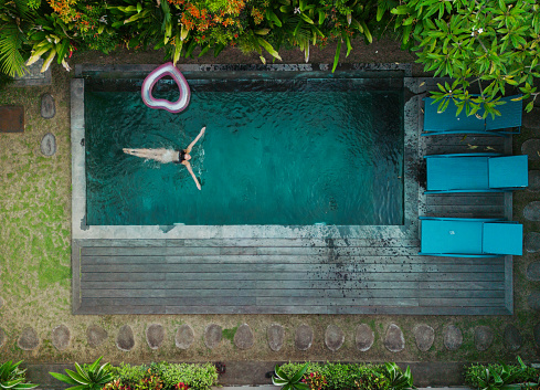 Aerial view of woman resting at swimming pool on villa