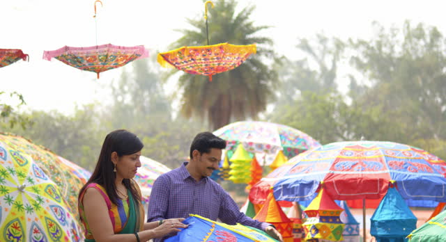 Happy couple buying colorful umbrella at carnival