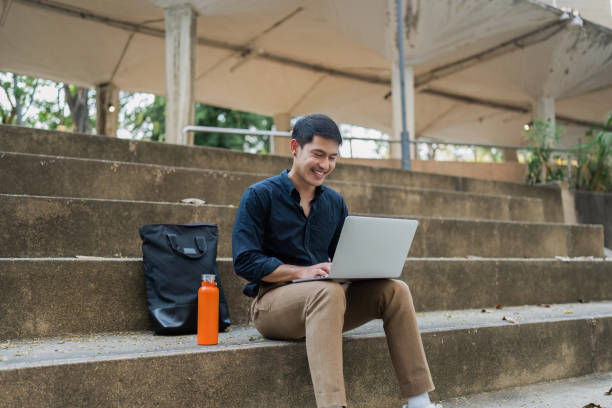 istock business man sitting on bench and working remotely on project with laptop 2067568574