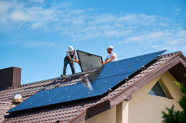 Workers building solar panel system on roof of house. Installers carrying photovoltaic solar module stock photo