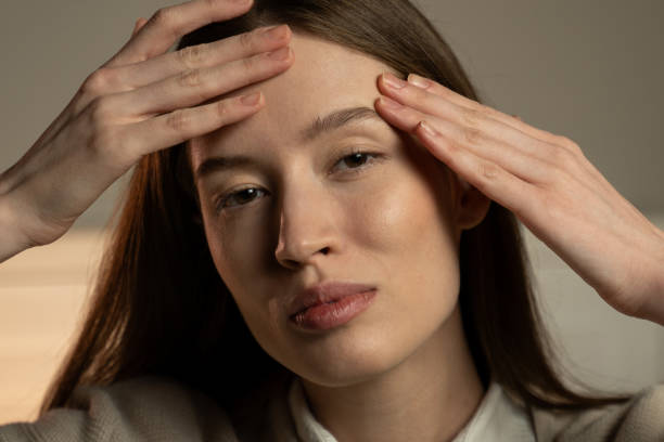 istock Serene Young Woman Gently Touching Her Head Indoors During Daytime 2067597891
