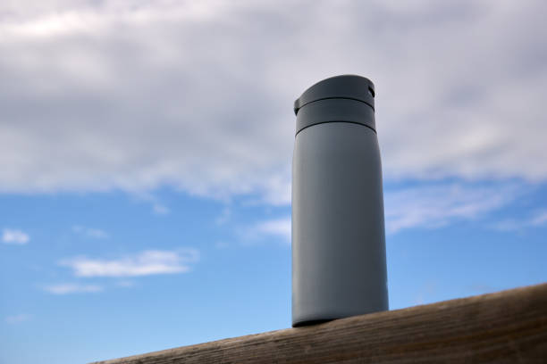 空を背景に木の柱に置かれた灰色の水筒