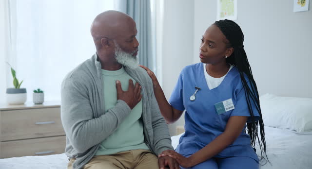 Senior care, nurse and black man with pain in chest with advice, healthcare and exam on bed. Homecare, heart and mature person with caregiver in consultation for medical assessment, support or help.