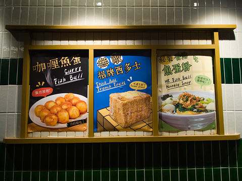 Chinatown, Sydney, Australia - April 17 2022 : A brightly light three distinctive food signs translated as Curry Fish Ball, HK Fish Ball Noodle Soup and wait for it, Thick Ass French Toast.