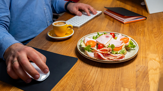 Businessman enjoying a healthy meal and coffee while working at a modern workspace