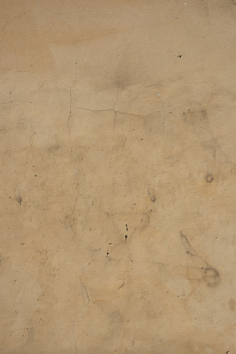 Close-up on an old dirty beige concrete wall.