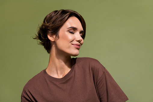Photo of gorgeous positive pretty girl with bob hairdo dressed brown t-shirt eyes closed enjoy moment isolated on khaki color background.