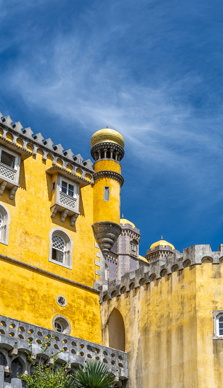 Exterior view of the watchtower of the colorful yellow Pena Palace under a sunny blue sky. Sintra. Portugal. Copy space. Vertical banner.