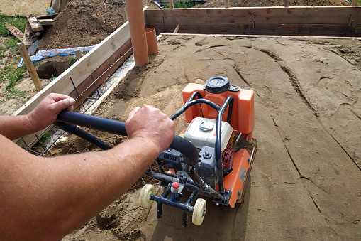 Working with a vibrating machine and equipment, soil compaction with a vibrating plate.new