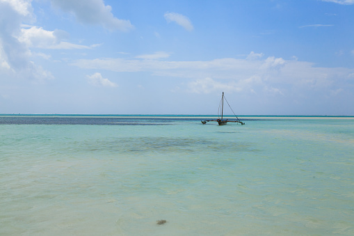 A boat in shallow waters with a blue sky background