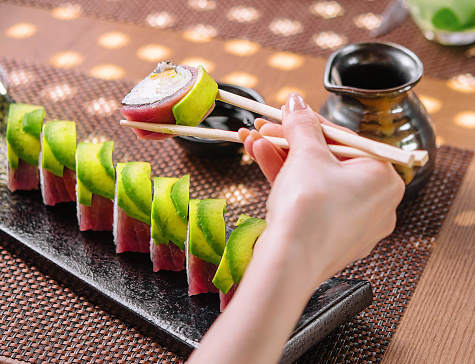 girl eating sushi rolls wrapped with tuna and avocado