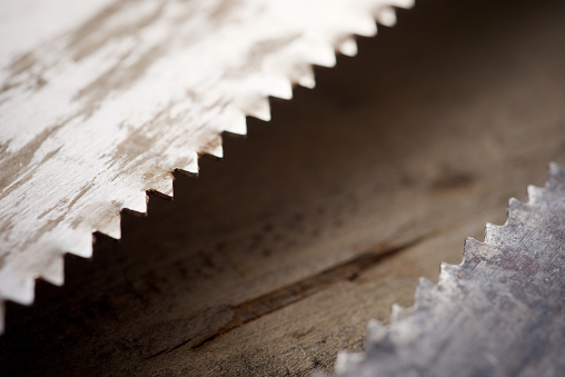 Close up of the serrated blade of an old handsaw on a work bench.