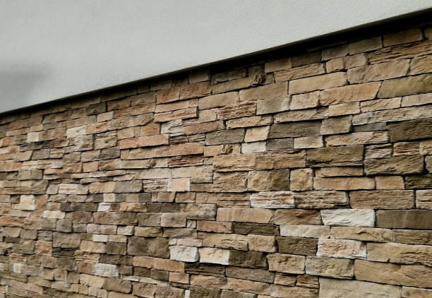 Modern gray brown, beige, metal door at the house lined with stone cladding. gutter for drainage of water on the pavement. limestone cladding