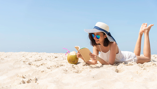 young brunette relaxing on the beach, reading a book.travel holidays concept